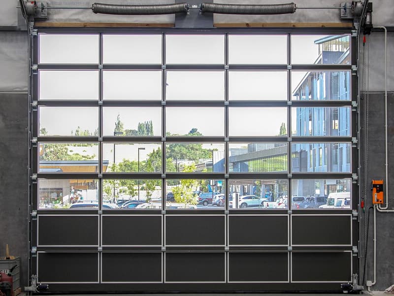 Full view glazed sectional door with black bottom panels in a workshop.